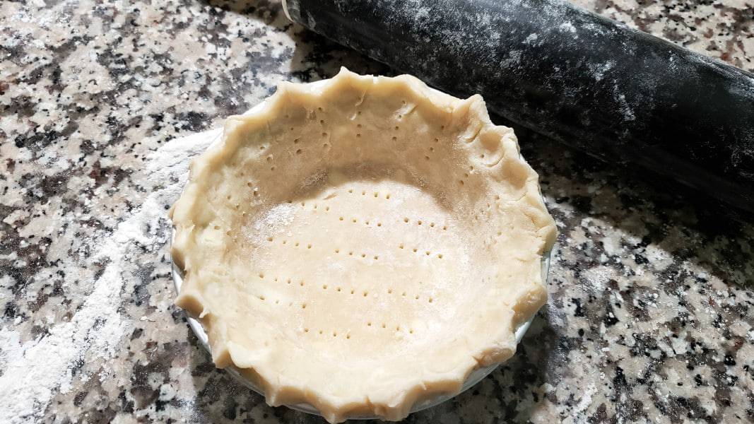 small batch pie crust dough with pinched edge in a pan.