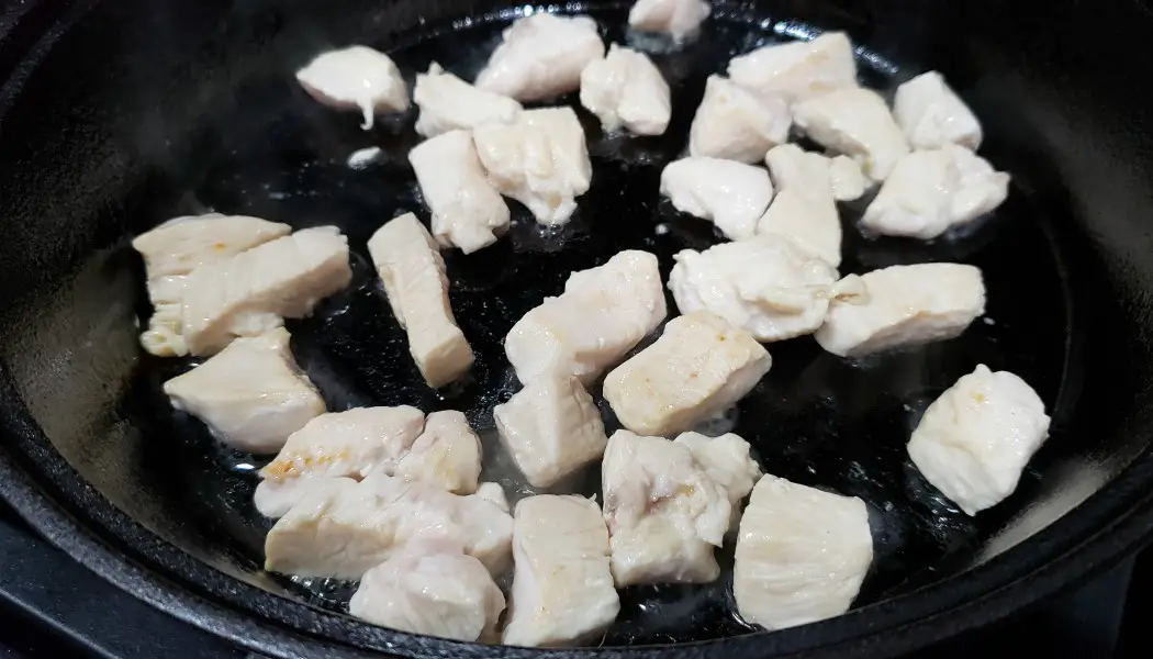 diced chicken cooking in a cast iron skillet
