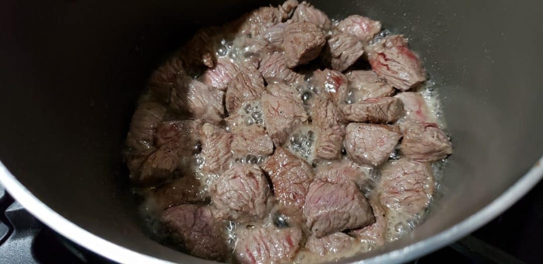 beef stew meat cooking in a pan