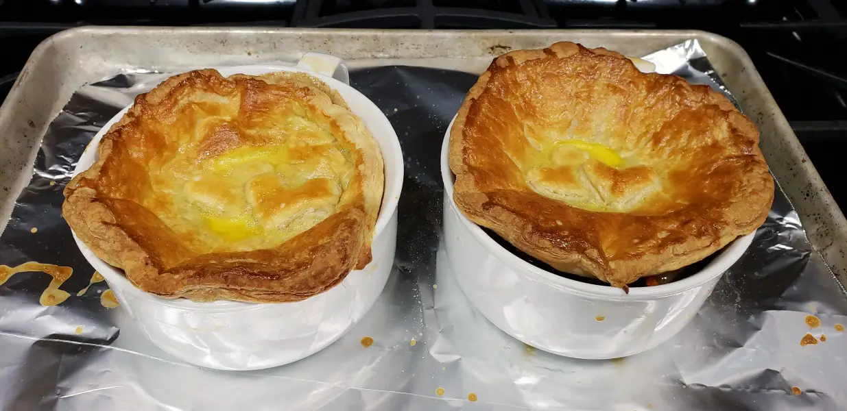 two baked beef pot pies with golden puff pastry