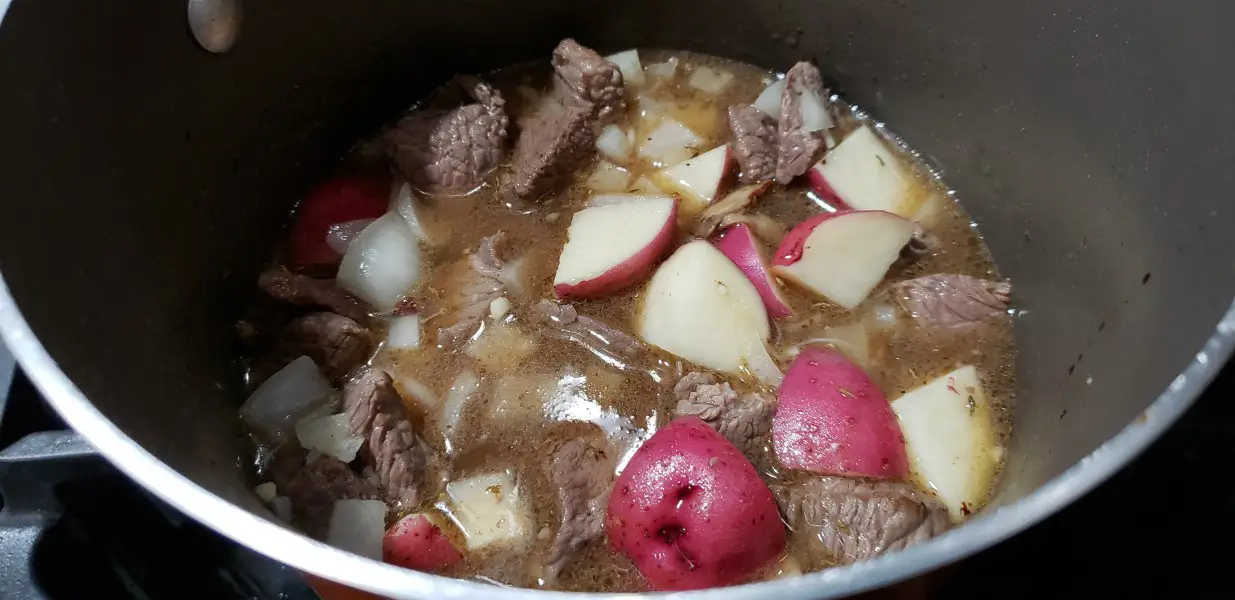potatoes, onions, and cooked beef stew meat added to pan