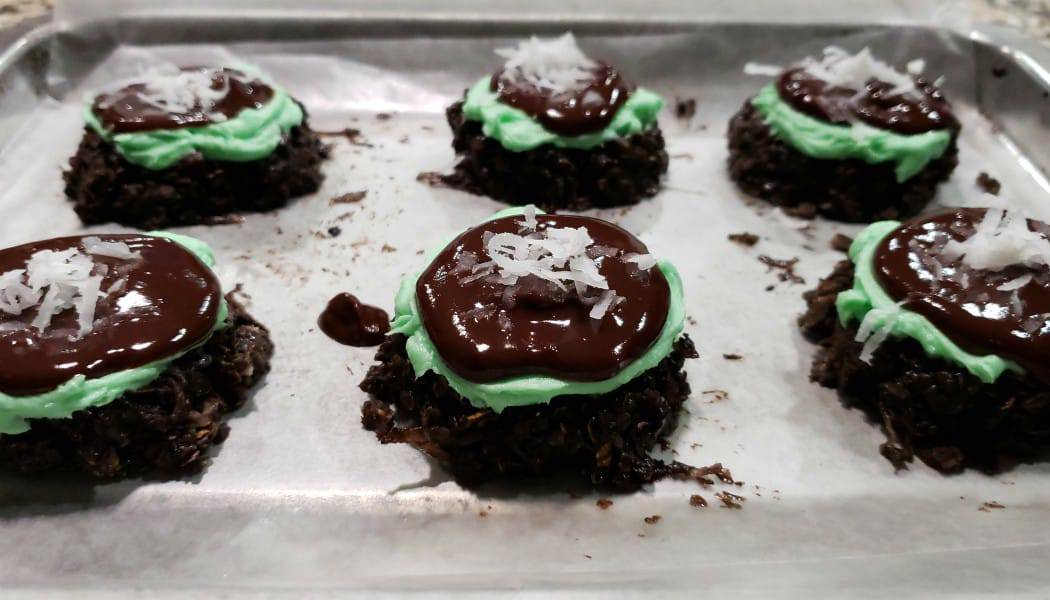 6 no bake cookies with green mint frosting and chocolate ganache and coconut on top