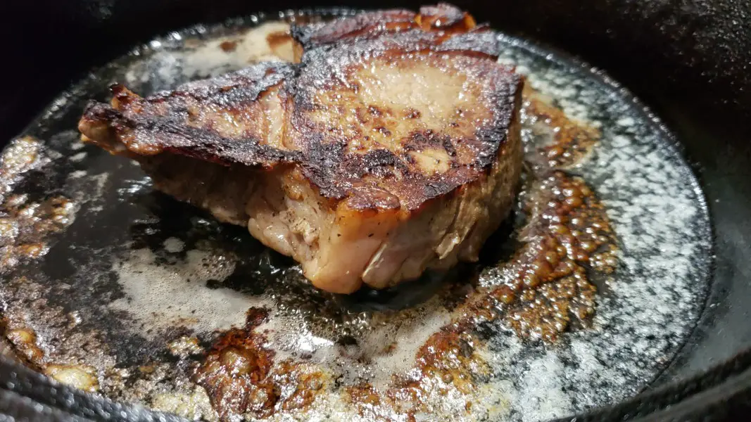 ribeye steak frying in a pan