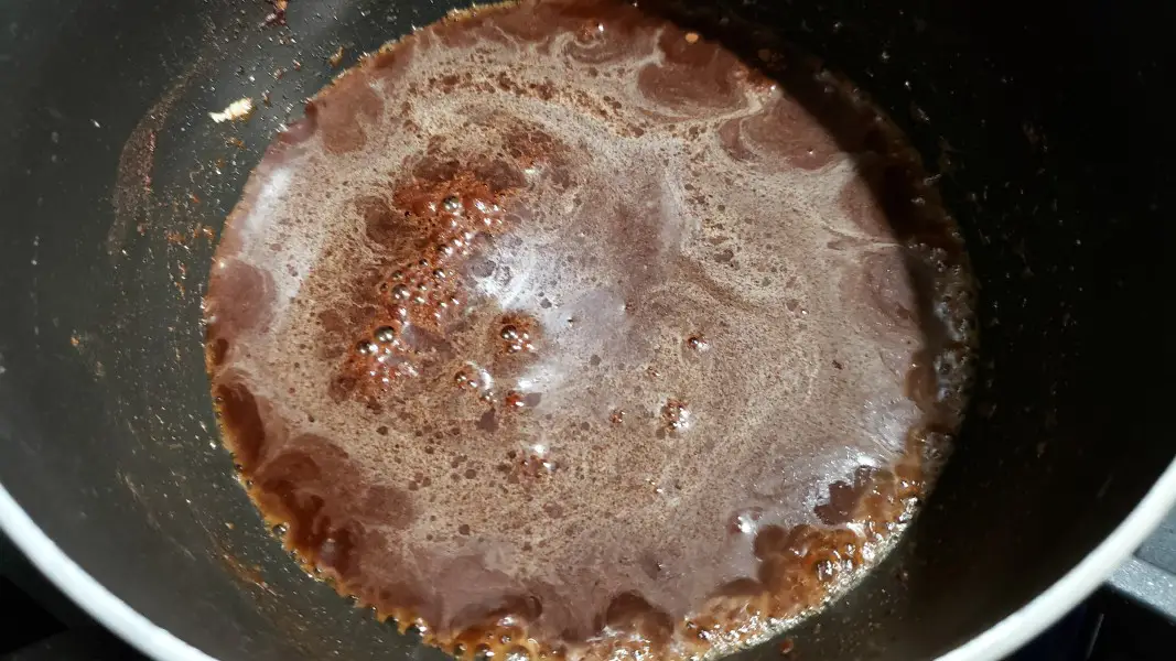 water, sugar, cinnamon, and vanilla cooking in a pan.
