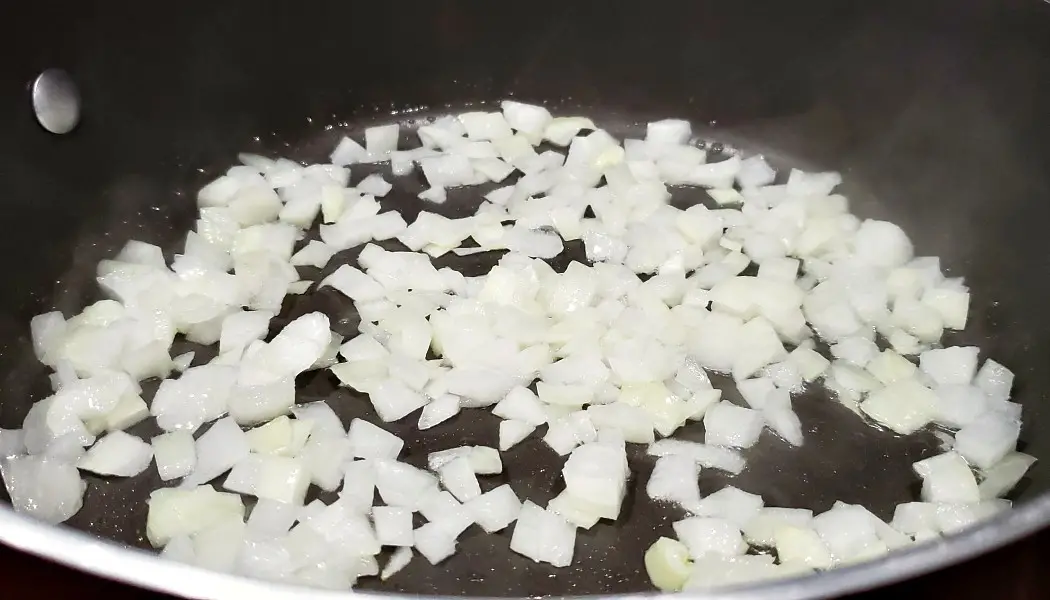 diced onions cooking in a frying pan