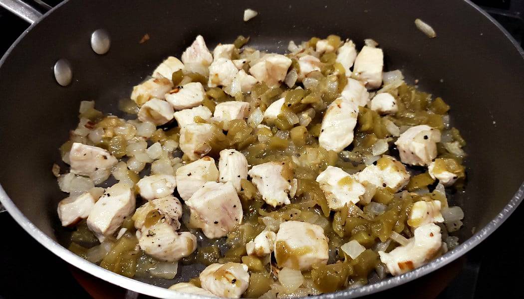 chicken, onion, and green chiles cooking in a frying pan