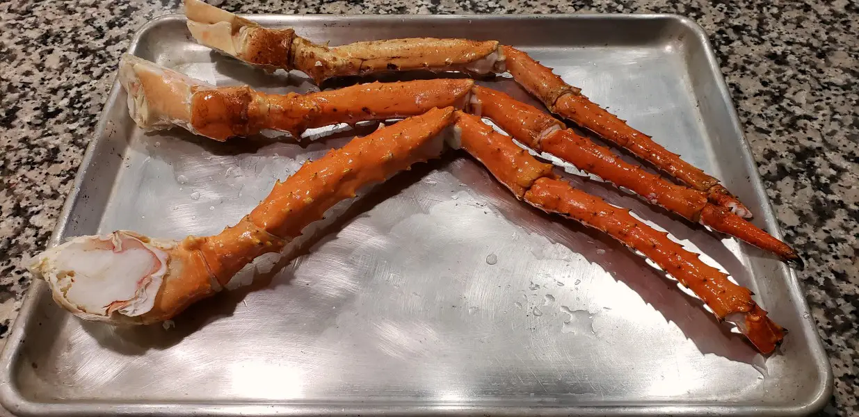 three king crab legs on a baking sheet