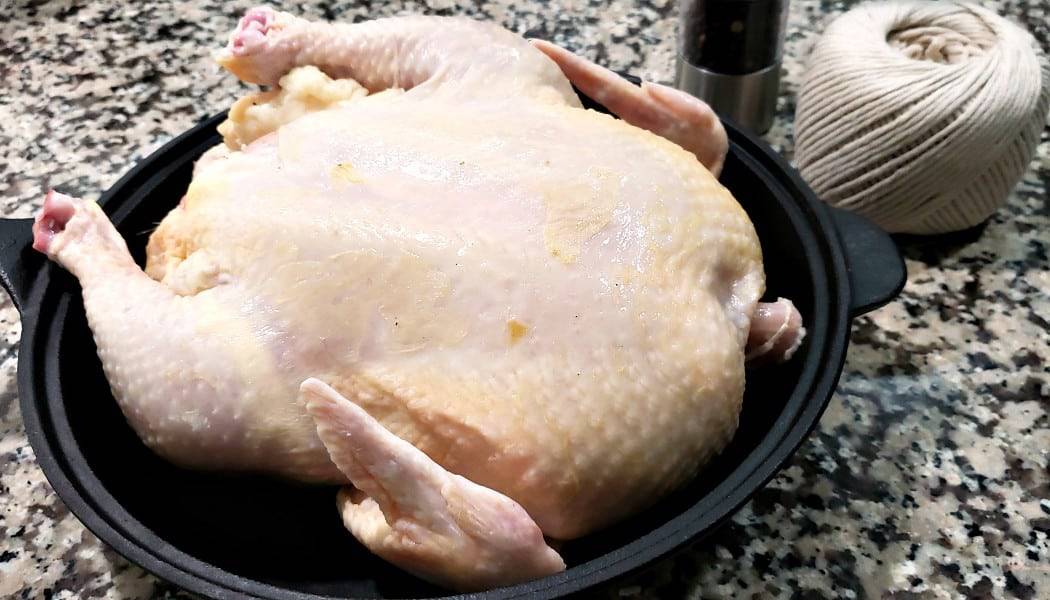 a whole chicken in a cast iron skillet.