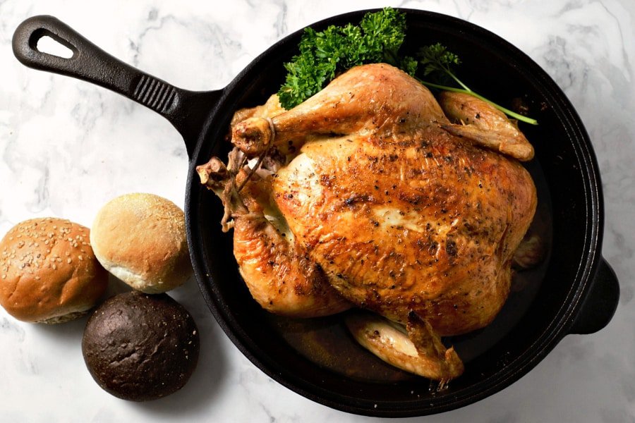 Easy Juicy Whole Roasted Chicken baked in a cast iron skillet.