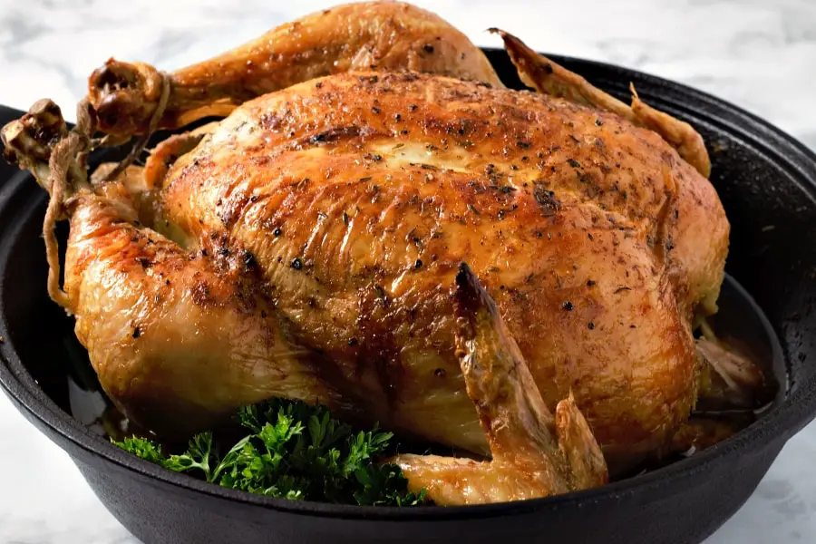 a baked whole Easy Juicy Roast Chicken in a cast iron skillet.