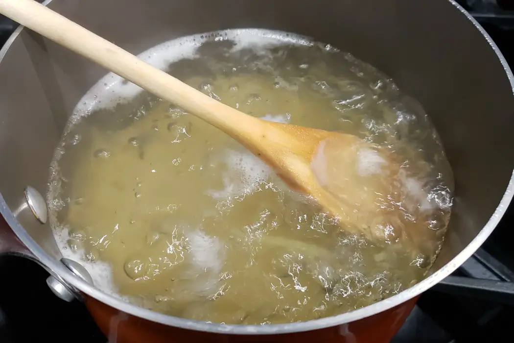 liguine boiling in a pan with a wooden spoon