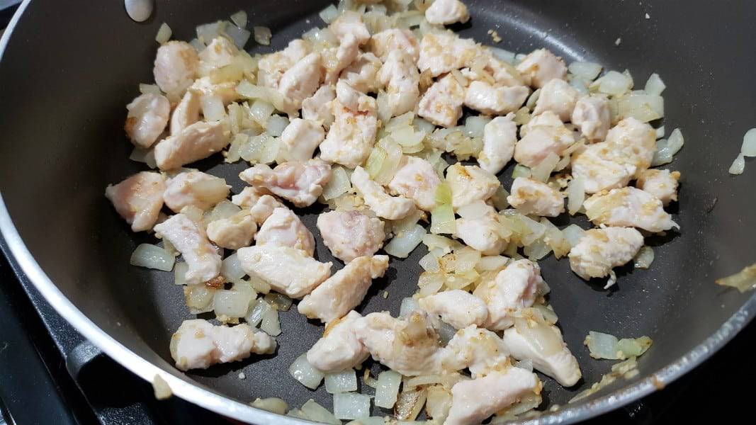 diced chicken, onion, and garlic cooking in a skillet