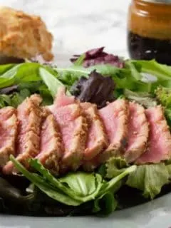 Sesame Seed Tuna Steak Salad on a plate with Asian Ginger Dressing.