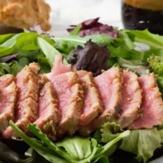 Sesame Seed Tuna Steak Salad on a plate with Asian Ginger Dressing.