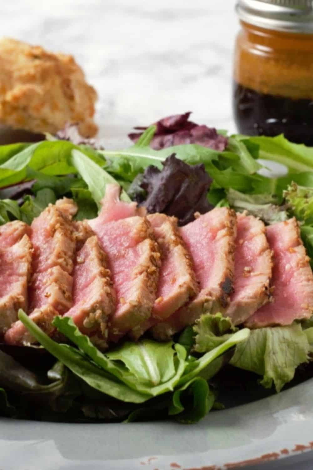 Sesame Seed Tuna Steak Salad on a plate with Asian Ginger Dressing.