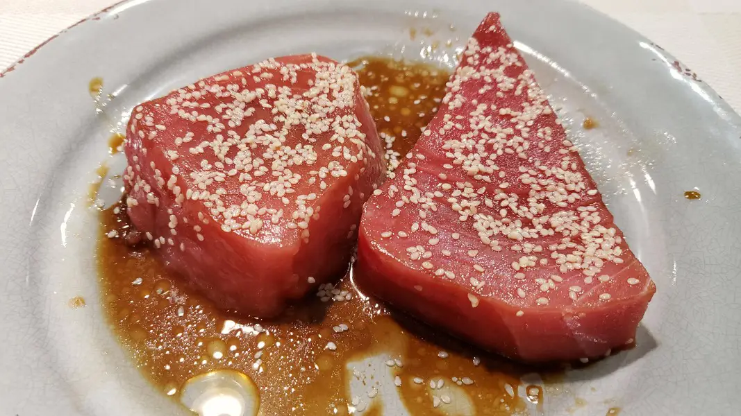 two raw tuna steaks coated in sesame seeds