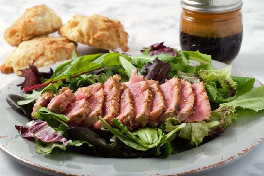 Seared Tuna Salad on a plate with a jar of Asian Ginger Dressing