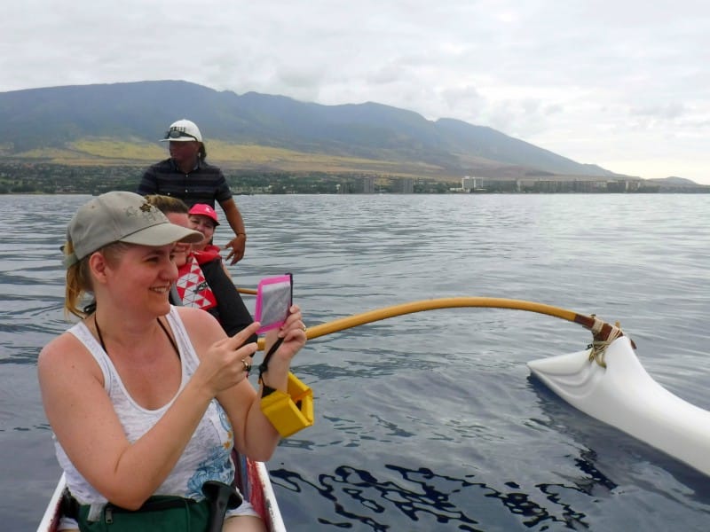 3 women and a man in an outrigger canoe