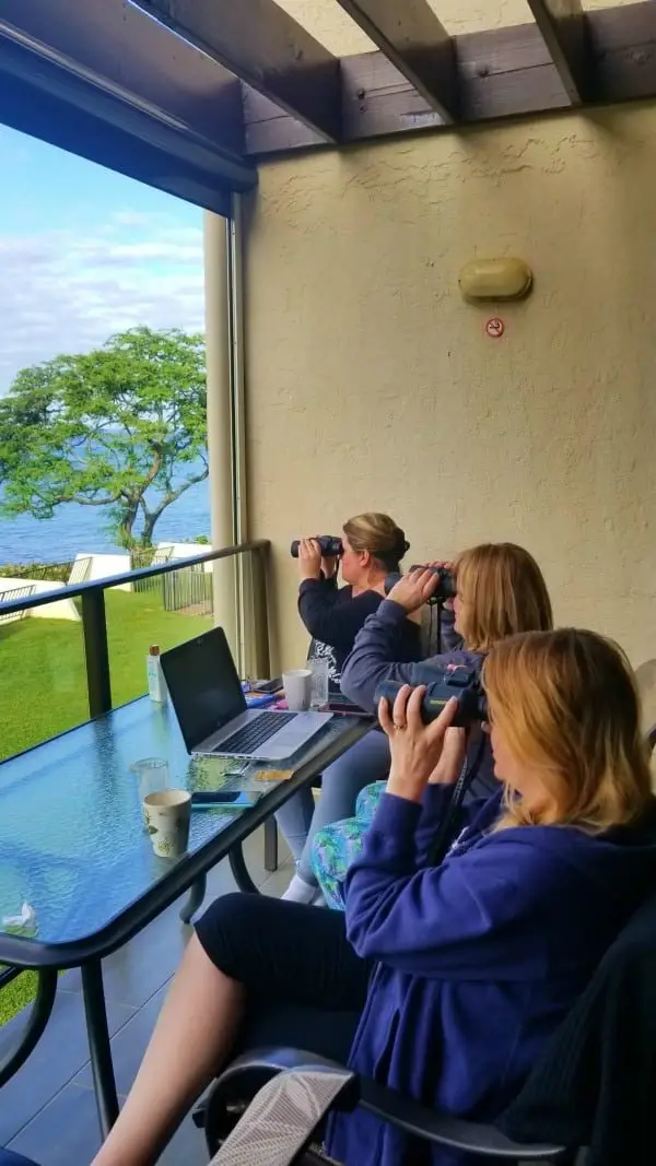 3 women looking at the ocean through binoculars