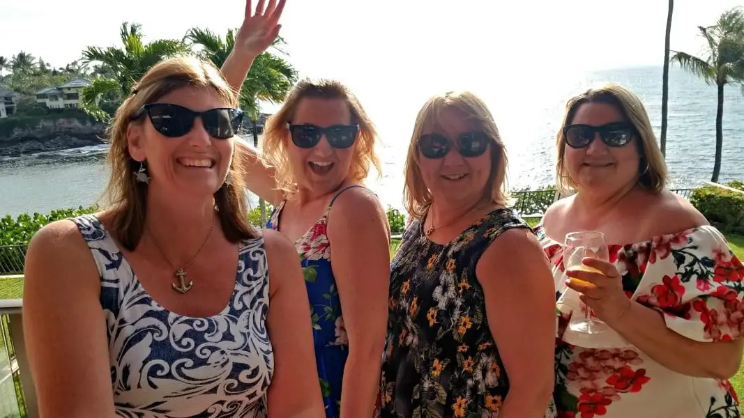 4 women in dresses with sun glasses on in front of an ocean view