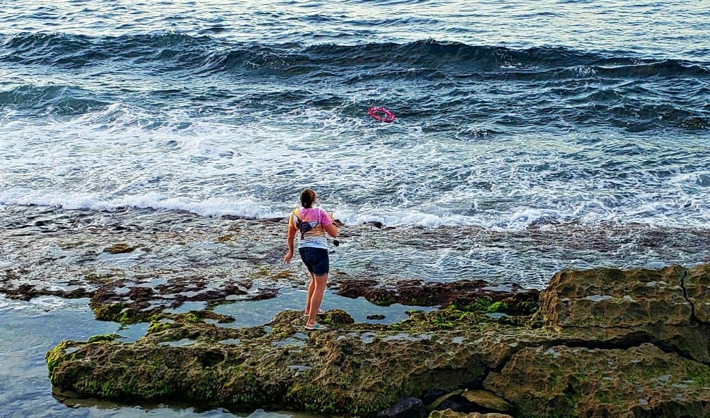 a woman tossing a lei into the ocean