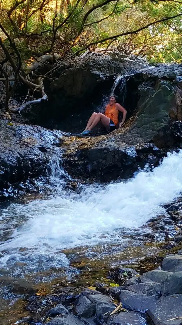 a women sitting under a small waterfall