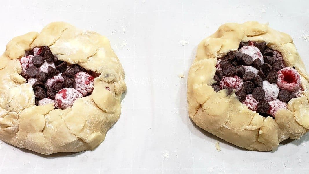 two unbaked raspberry galettes on a baking sheet