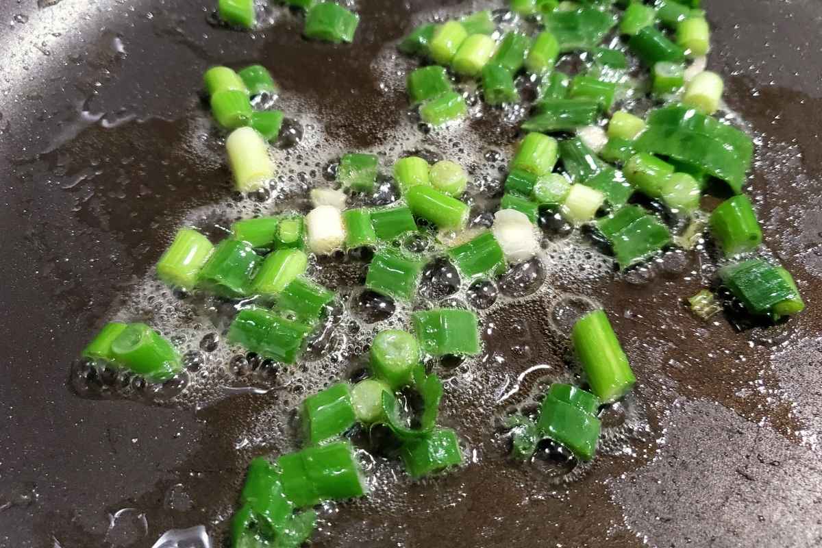 green onions cooking in a skillet.