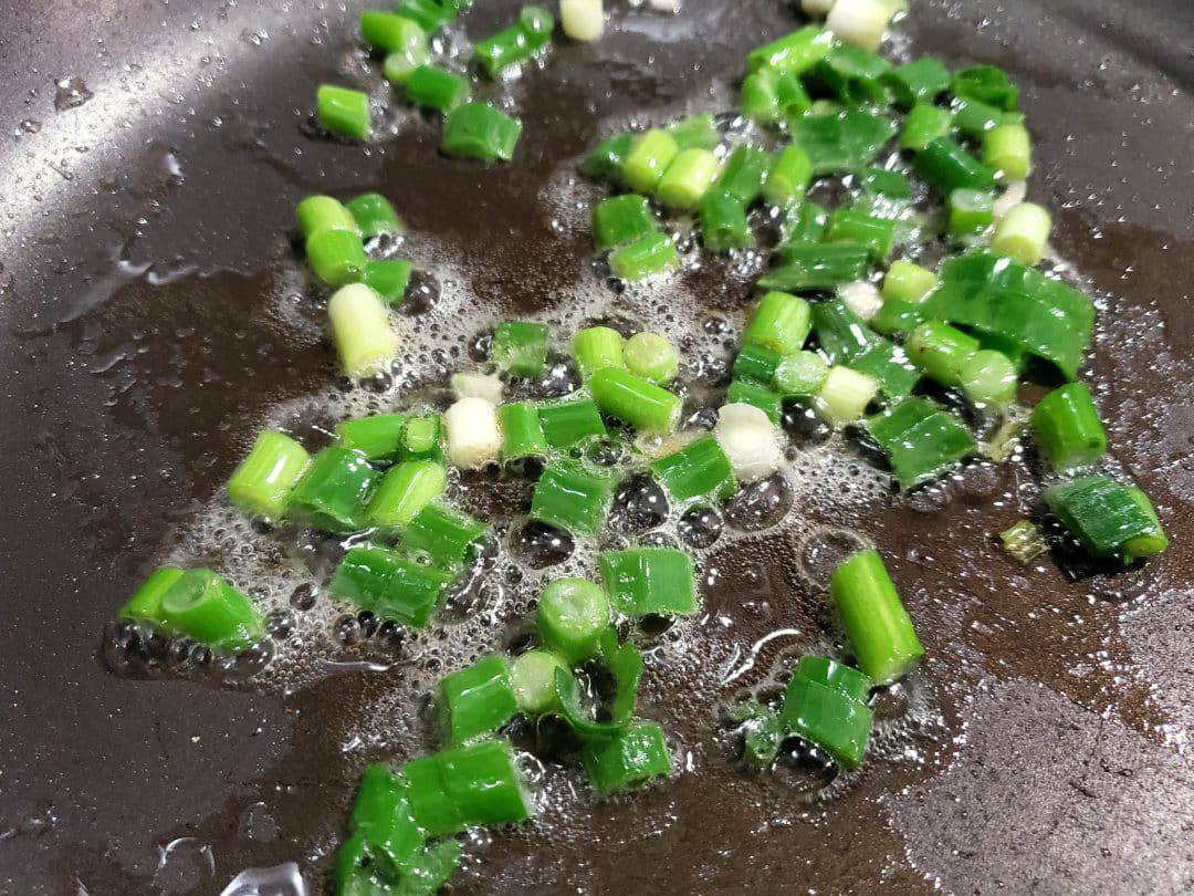 green onions cooking in a skillet