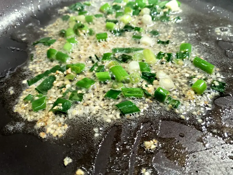 green onions, garlic, and chicken broth cooking in a pan