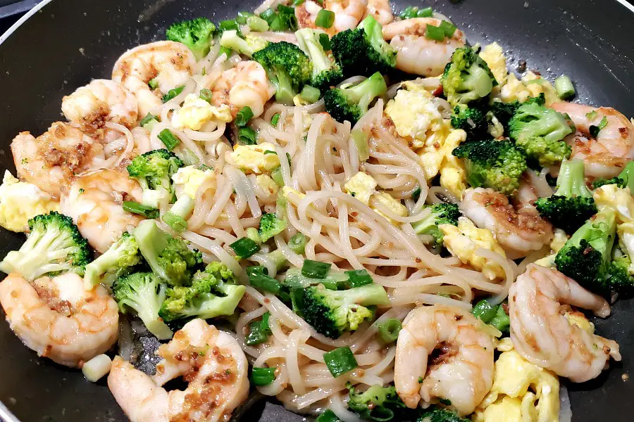 shrimp pad Thai heating in a pan