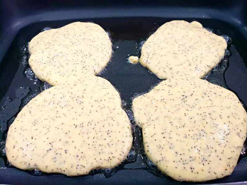 4 lemon poppy seed pancakes cooking in a skillet