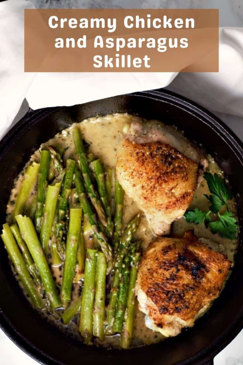 A Cast Iron Skillet filled with Creamy Chicken Thighs and Asparagus.