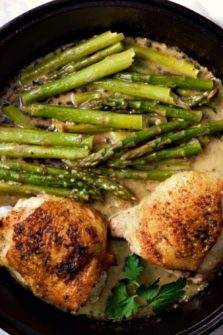 Skillet Chicken Thighs and Creamy Asparagus in a cast iron skillet.