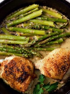 Skillet Chicken Thighs and Creamy Asparagus in a cast iron skillet.