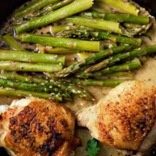 Skillet Chicken Thighs and Creamy Asparagus in a cast iron skillet.