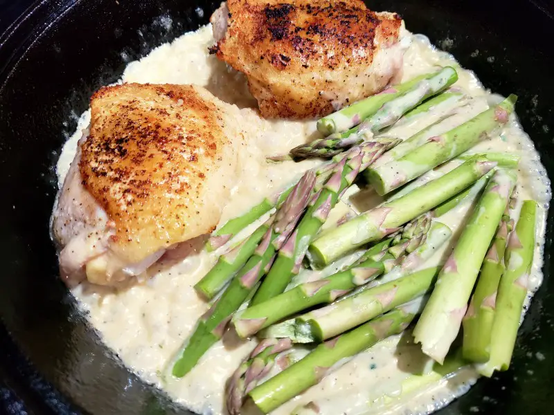 Creamy Chicken and Asparagus cooking in a cast iron Skillet 