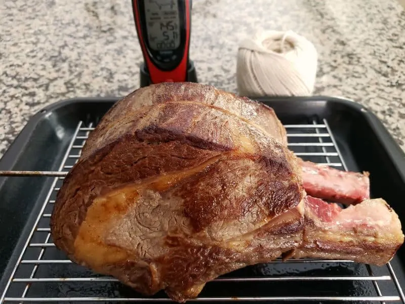 a beef roast on a roasting rack with a meat thermometer inserted