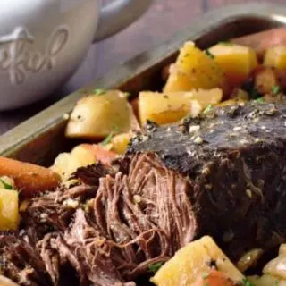 Slow Cooker Pot Roast Dinner on a tray with a side of gravy.