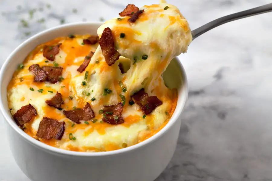 Loaded Mashed Potato Casserole with a spoon pulling a bite out