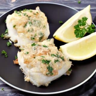 Skillet Roasted Cod with Garlic Butter on a plate with lemon wedges