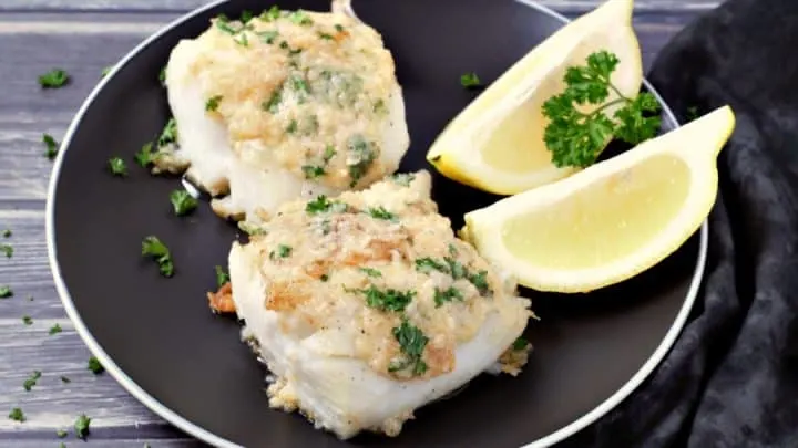 Skillet Roasted Cod with Garlic Butter on a plate with lemon wedges