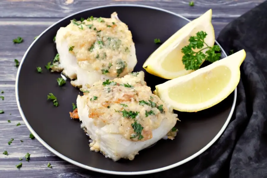 Garlic Butter Cod on a plate with lemon wedges