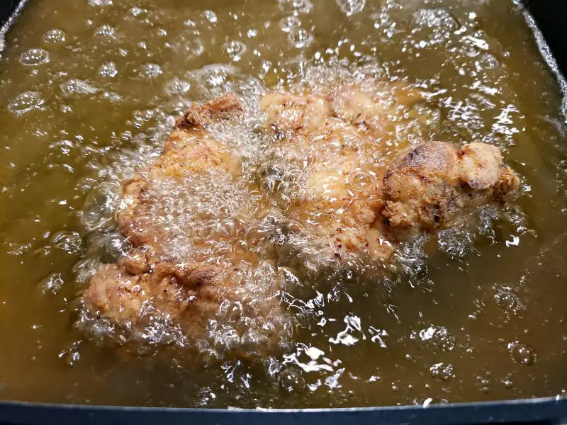 breaded chicken thigh frying in oil