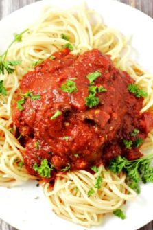 Slow Cooker Chicken Cacciatore over spaghetti on a plate.