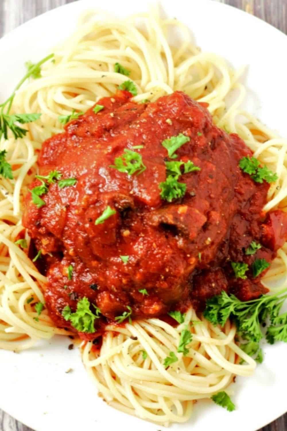 Slow Cooker Chicken Cacciatore over spaghetti on a plate.