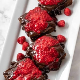 Brownies with Raspberry Sauce and Chocolate Ganache on a plate.