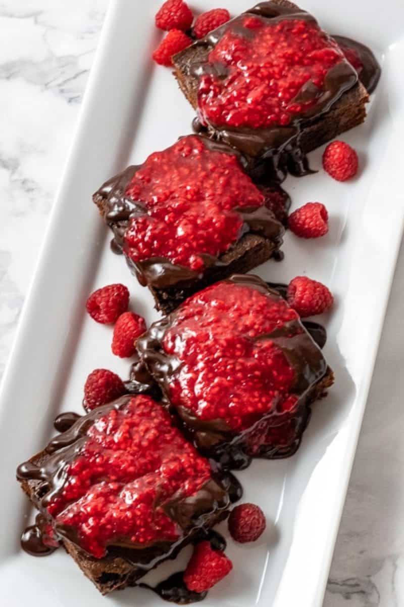 Brownies with Raspberry Sauce and Chocolate Ganache on a plate.