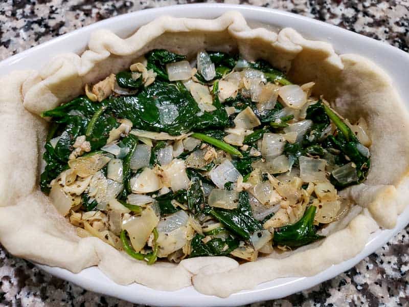 spinach, artichoke, and onion mixture added to the pie crust.