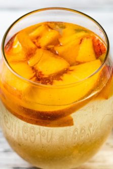 a glass of Peach Sangria with fresh peaches floating on top.